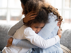 Adult woman hugging a child in need.