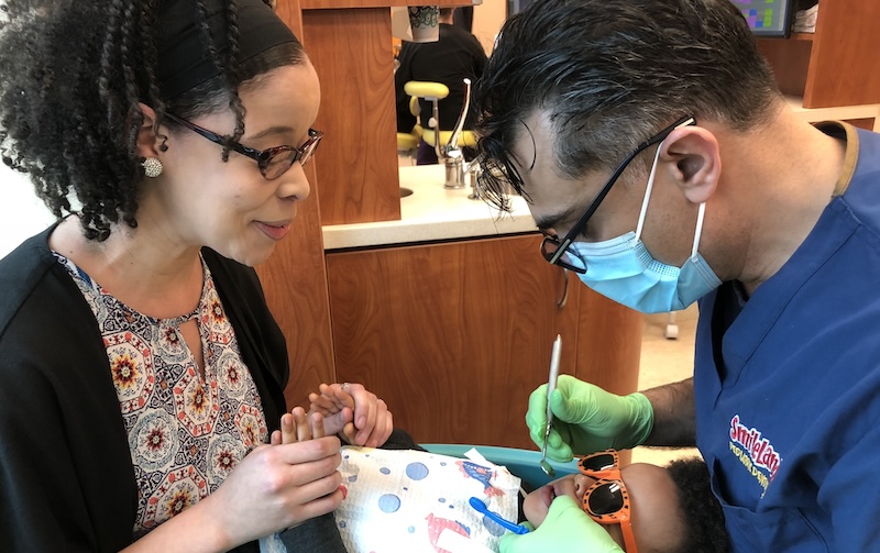 Dentist and assistant looking at a child's teeth.