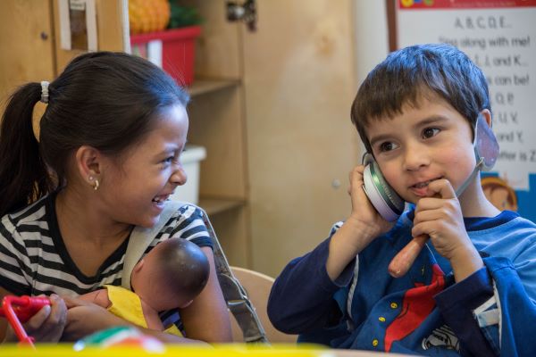 Boy playing telephone by placing a cooking spatula up to his ear and mouth.